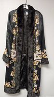 Full view of the black silk robe hanging, featuring colorful embroidery and black fur trim along collar, cuffs, and hem.
