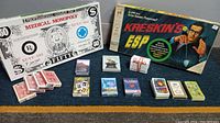 Photo showing Medical Monopoly box, Creskins ESP game box, and multiple small decks of playing cards arranged on a blue surface.