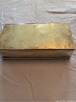 Closed view of silver rectangular metal box with beaded edge detail, mild tarnishing visible
