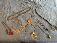 Overview of the eight costume jewelry necklaces laid out on a fabric surface showing various styles and pendants.