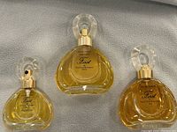 Three bottles of First Eau de Toilette by Van Cleef & Arpels in spray bottles, one 30ml and two 60ml showing liquid levels and label details.