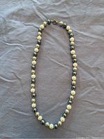 Full view of the necklace laid flat showing alternating white and grey freshwater pearls, end to end.