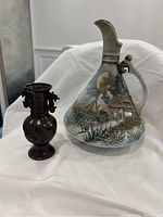 Photo of bronze vase and hand-painted Nippon vase side by side on white fabric background