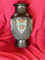 Full view of the Japanese ceramic vase showing heraldry-style decoration in blue, red, and white on a dark textured body.