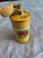 Close-up front angled view of the yellow cylindrical perfume atomizer with red poppies hand painted on the body and gold-tone spray top with mustard fabric bulb pump.