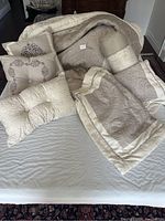 Photo showing queen size beige/vanilla bedspread with folded edges and four decorative pillows arranged on bed