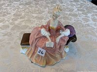 Front view of the Royal Doulton 'Reverie' figurine showing the seated woman in the peach and pink gown holding a book.
