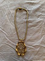 Full view of the sterling silver pendant on the chain laid flat on a fabric surface, showing the pendant's irregular open lattice design and the chain's woven pattern.
