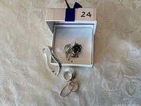 Top-level view of all sterling silver jewelry items including bracelet, brooch, rings, and earring on a light background with box.