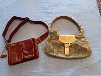 Both purses laid side by side on a fabric background: a leopard print and tan leather Browns ID shoulder bag, and a burgundy leather Danier crossbody bag with a wide strap.