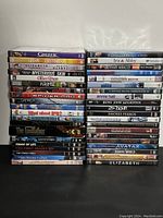 Photo showing stacks of assorted DVD movie cases with visible titles and cover art.