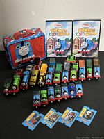 Wide view showing over 30 die cast trains in different colors and characters, Thomas & Friends Toy Workshop DVDs, metal lunchbox, and collectible item cards