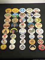 Collection of 40 assorted vintage and retro button pins, shown laid out flat in rows showing front designs including promotional, political, event, and novelty themes.