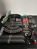 Two sets of Carrera Go!!! Mario Kart slot car racing tracks with Mario and Luigi cars, controllers, and accessories arranged on white surface with some track pieces bundled by rubber bands
