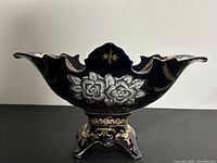 Side view of the cobalt blue fruit bowl showing white and gold floral decorations and scalloped edges.