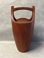 Front view of closed teak ice bucket with integrated swing handle raised, lid in place