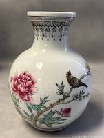 Front angle of the vase showing bird perched on floral branch with peony flower and decorated neck rim