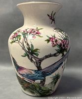 Front view of 8 inch vintage ceramic vase with detailed bird painting and flowering tree branch design on cream background.