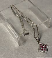 Photo showing 17 inch silver rope chain with attached square pendant containing 9 red rubies.
