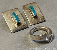 Photo showing pair of rectangular silver earrings with turquoise center stones alongside solid silver ring with unique design and clear hallmarks inside band.
