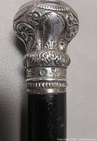 Close-up of the sterling silver handle with hallmark stamps and ornate design on the cane.