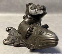 Front three-quarter view of the bear seated on the salmon base, showcasing overall form and carving detail