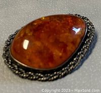 Close-up side angle of polished natural amber stone with silver rope border setting