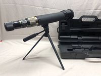 Telescope on tripod with case in background showing the entire setup and included case.