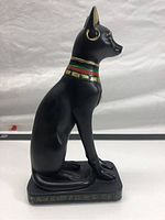Side profile of the black Bastet statue showing the gold earring, colored collar, and hieroglyphic-decorated base.