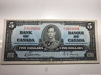 Front view of a 1937 Bank of Canada $5 banknote featuring King George VI portrait with red serial numbers E3039096 and bilingual text.