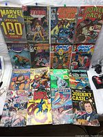 Full lot of 16 mixed comic books with various superhero and music themes laid out on a flat surface.