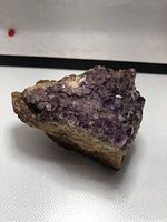 Side angle showing purple amethyst crystals on earthy base.