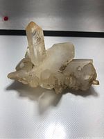 Front and top angled view showing multiple clear quartz points in the cluster with translucent, milky hues and some surface mineral deposits.