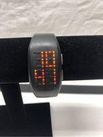 Front view showing LED time display lit up (19:19) on black Philippe Starck PH-1055 wristwatch.