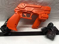 Orange Namco Guncon 3 light gun showing right side with trigger and safety warnings.