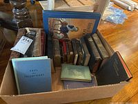 Box containing multiple religious books including Holy Bible 1940 edition, Paul the Triumphant, black Oxford Encyclopedic Bible, and additional books of various sizes and colors