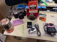 Photo showing entire lot with Zeiss Ikon Contaflex 126 camera with telephoto lens, instruction manual, red case, and two Innovage mini digital cameras with their cases and cables.