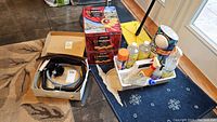 Photo of all items together on floor including mop, metal tins, cleaning bottles, and dryer vent cleaning kit.