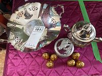 Metal tray, sugar pot with etched silver lid, and six gold salt and pepper shakers arranged on a red quilted surface.