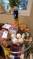 Full lot view on glass table including baseball gloves, baseballs, marbles jar, and Tai Chi kit boxes.