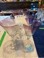 Six purple shade wine glasses arranged on a table, showing the gradient color and clear stems.