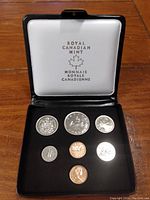 Opened Royal Canadian Mint white display case with seven Canadian coins arranged inside.