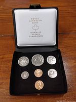 Photo of the full coin set displayed in opened black velour and white case branded Royal Canadian Mint with seven coins.