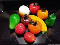 Glass fruit figurines arranged together on a black surface