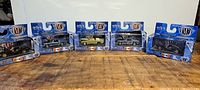 Five unopened die-cast Mustang model cars in original M2 Machines Detroit Muscle packaging lined up on a wooden surface.