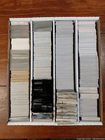 Top-down view of a cardboard box filled with multiple rows of tightly stacked non-sport collectible cards in loose form.