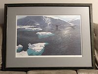 Photo of framed print showing the icy ocean and whale tails scene in landscape orientation.