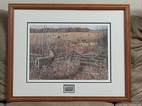 Overall view of framed print depicting deer in an autumn field near rustic wooden fence.
