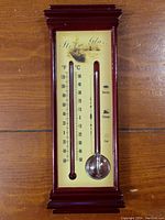 Full view of rectangular wooden framed Storm Glass and Thermometer unit on wooden floor showing combined weather prediction and temperature measurement.