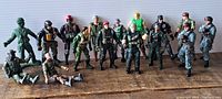 Full view of 16 toy soldier action figures standing and sitting on a wooden surface, showing different military attire and colors